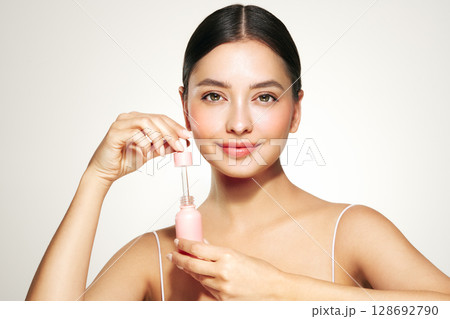 Woman holding a cosmetic jar of oil serum Woman holding a cosmetic jar of oil serum 128692790