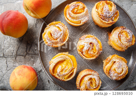 puff pastry peach roses mini tarts muffins close-up on a plate. horizontal top view 128693010