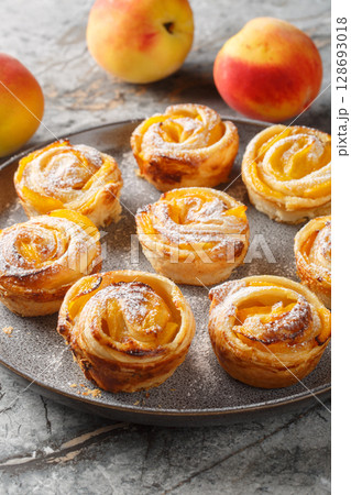 puff pastry peach roses with fresh fruits and powdered sugar close-up on a plate. Vertical 128693018