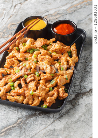 Crisp pork surou or xiaosurou consists of fatty meat that is coated in a batter containing eggs and subsequently deep-fried closeup on the plate. Vertical 128693031