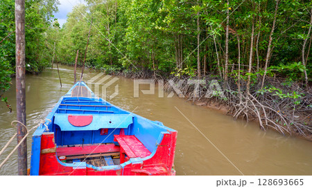 Colorful Wooden Boat Cruising Through Mangrove Forest River in Southeast Asia Colorful Wooden Boat Cruising Through Mangrove Forest River in Southeast Asia 128693665