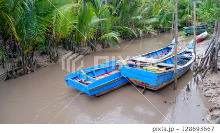 Traditional Wooden Boats Moored on a Tropical Mangrove Riverbank 128693667