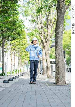 作業着のミドル男性 歩く スマホ 作業着のミドル男性 歩く スマホ 128694510