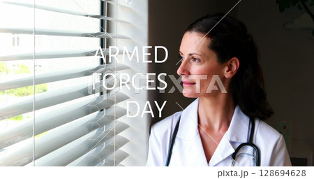 Image of armed force day over thoughtful caucasian female doctor standing at window Image of armed force day over thoughtful caucasian female doctor standing at window 128694628