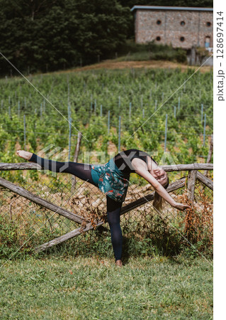 Ballerina Performing Graceful Stretch in Vineyard Setting Ballerina Performing Graceful Stretch in Vineyard Setting 128697414