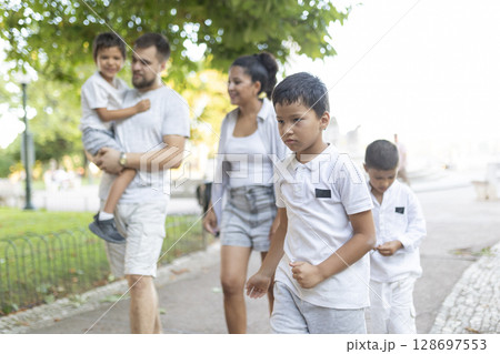 Sad child walking with family in park during summer day Sad child walking with family in park during summer day 128697553