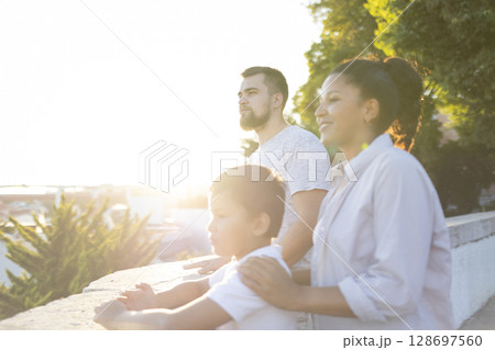 Happy family watching sunset from city wall at golden hour 128697560