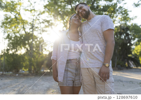 Happy couple embracing in park at sunset, enjoying romantic moment 128697610
