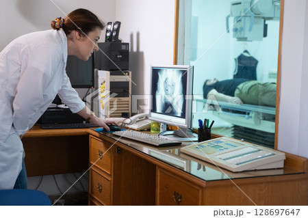 Radiologist Analyzing X-Ray Scans in a Medical Imaging Room. Radiologist Analyzing X-Ray Scans in a Medical Imaging Room. 128697647