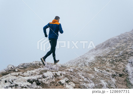 Man Climbing Rocky Hill in Fog 128697731