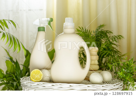 Natural cleaners, cleaning products, natural detergent bottles with soap, lemon and brush on wooden podium in home interior with home plants. Mockup for natural detergents and cleaning products 128697915