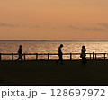 茨城県の北浦の夕日　夕日の湖を背景に歩く三人の若者のシルエット 128697972