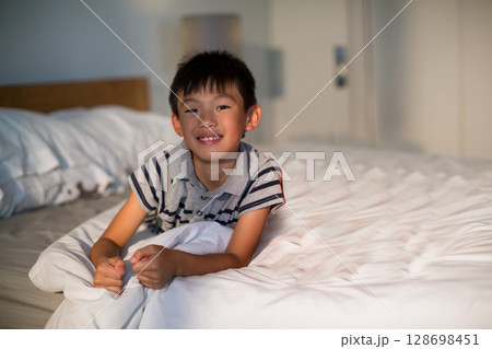 Smiling boy relaxing on bed at home, enjoying cozy morning light, copy space Smiling boy relaxing on bed at home, enjoying cozy morning light, copy space 128698451