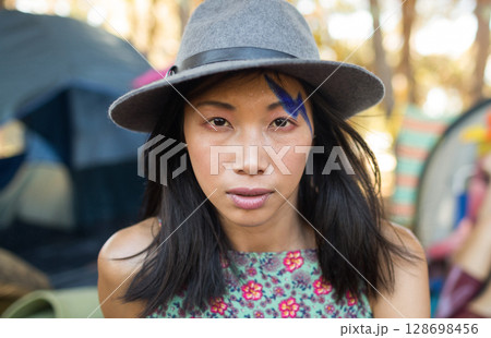 Woman in hat with face paint enjoying outdoor music festival atmosphere 128698456