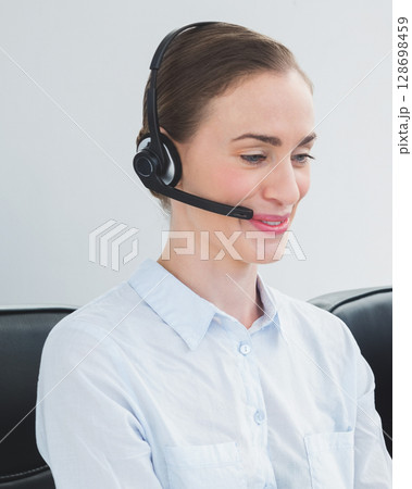 Wearing headset, customer service representative assisting clients with smile Wearing headset, customer service representative assisting clients with smile 128698459