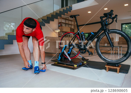 The triathlete putting on his sneakers and preparing for his home bike training . 128698605