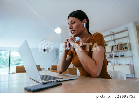 Woman sitting in living room using laptop looking at cam talk by video call with business friend relatives, head shot. Job interview answering questions 128698753