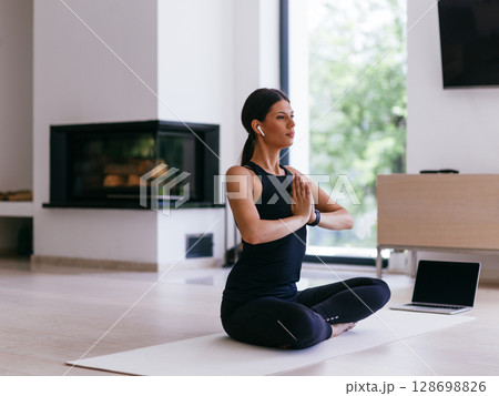 Young Beautiful Female Exercising, Stretching and Practising Yoga with Trainer via Video Call Conference in Bright Sunny House. Healthy Lifestyle, Wellbeing and Mindfulness Concept 128698826