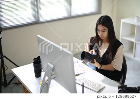 Female photographer carefully cleaning a camera lens at her modern editing workspace Female photographer carefully cleaning a camera lens at her modern editing workspace 128699627