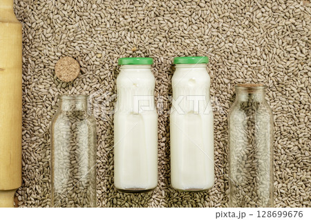Sunflower seed milk in glass bottles on background with sunflower seeds. Dairy free, non lactose plant milk. Raw diet meal. Healthy vegetarian or vegan food. Eco friendly product. Cooking of seed milk 128699676