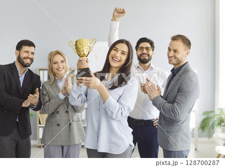 Happy business team holding golden trophy cup, clapping and celebrating great hard work success. 128700287