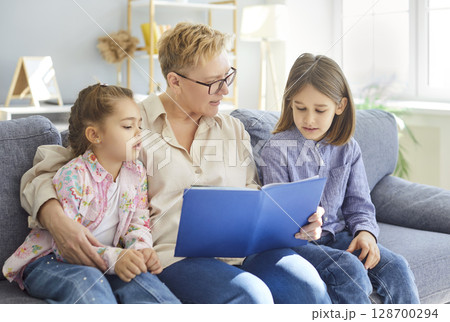 Grandmother Reading Book With Grandchildren At Home Grandmother Reading Book With Grandchildren At Home 128700294