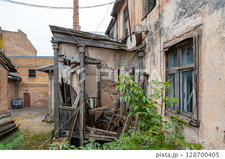 the yard of an residential area with an abandoned crumbling house 128700405