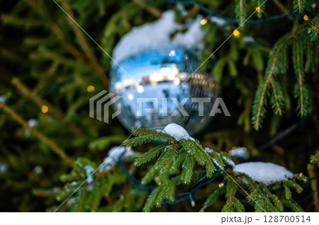 Christmas disco ball decoration on a snowy Christmas tree branch. Selective focus 128700514