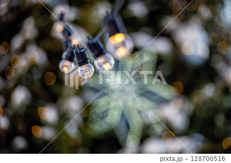 garland of light bulbs on defocused festive lights background, shallow depth of field, copy space 128700516