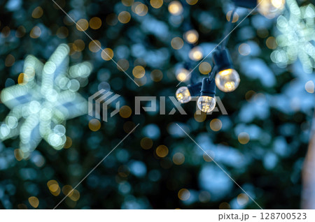 garland of light bulbs on defocused festive lights background, shallow depth of field, copy space 128700523