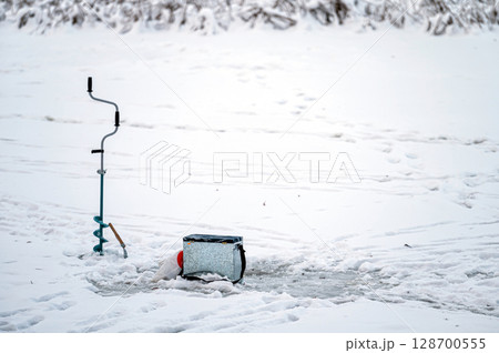 Fishing equipment for winter ice fishing on the background of a frozen river. 128700555
