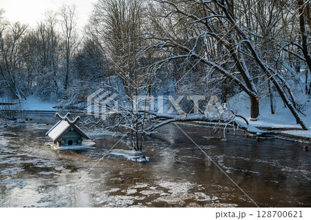 spring floods and ice melt in a small river, waterfowl feeder flooded as water level rises, Dobele spring floods and ice melt in a small river, waterfowl feeder flooded as water level rises, Dobele 128700621