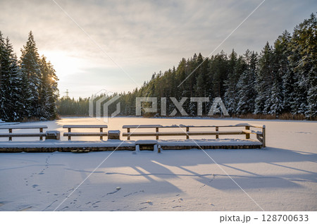 The snow on the snow-covered, forested Lake Melnezers, in the rays of the evening sun, Latvia The snow on the snow-covered, forested Lake Melnezers, in the rays of the evening sun, Latvia 128700633