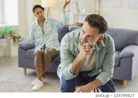 Emotional angry wife talking with her unhappy upset husband sitting at home 128700827