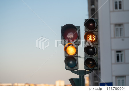Traffic lights show red and green signals, indicating movement for vehicles and buses. 128700904