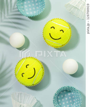 Summer sport activities and healthy lifestyle with tennis balls with smile faces, table tennis balls and shuttlecocks on blue background with palm shadows. Tennis, table tennis, badminton Summer sport activities and healthy lifestyle with tennis balls with smile faces, table tennis balls and shuttlecocks on blue background with palm shadows. Tennis, table tennis, badminton 128700919