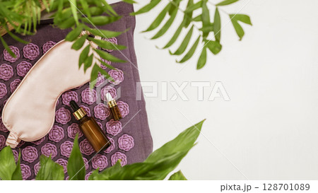 Self care flat lay with mask for sleep, dropper bottles with natural oils on massage relax mat with home plants. Concept of Relaxing at home, Me time, take care, healthy and good sleeping. Copy space 128701089