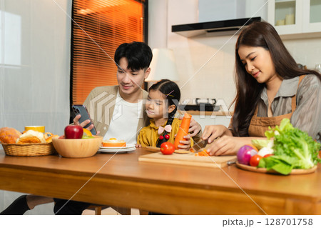 Smiling Asian family enjoying breakfast in weekend morning. Smiling Asian family enjoying breakfast in weekend morning. 128701758