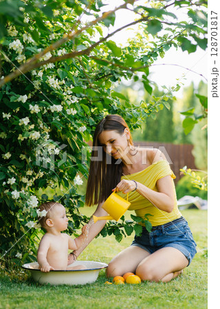 Mother and Baby Playing with Watering Can Outdoors Mother and Baby Playing with Watering Can Outdoors 128701817