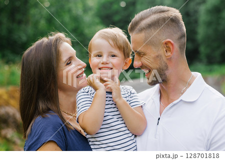 Happy Child Smiling Between Loving Parents Outdoors 128701818