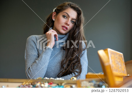 reflection of a woman in mirror choosing and trying different jewelry, soft focus, closeup reflection of a woman in mirror choosing and trying different jewelry, soft focus, closeup 128702053