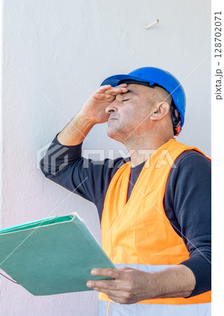 Tired and exhausted mechanical technician or building contractor. Bad news triggering headache Tired and exhausted mechanical technician or building contractor. Bad news triggering headache 128702071
