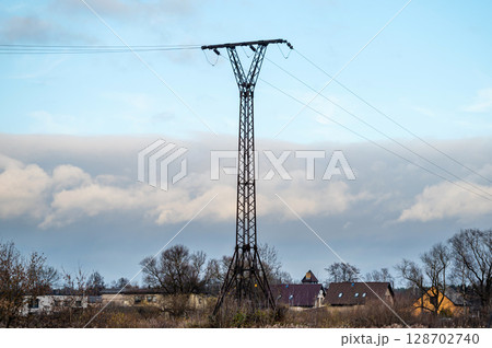 A metal support for a power line on the background of a summer cottage village. 128702740