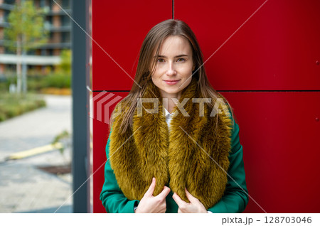 portrait of a woman at the red wall of a modern office building on a cool autumn day 128703046