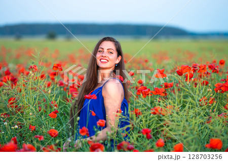 pretty young woman with long hair playing with petals in poppy field in evening sunlight pretty young woman with long hair playing with petals in poppy field in evening sunlight 128703256
