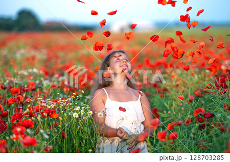 cute girl wearing white dress in summer blooming poppy field playing under evening sun cute girl wearing white dress in summer blooming poppy field playing under evening sun 128703285