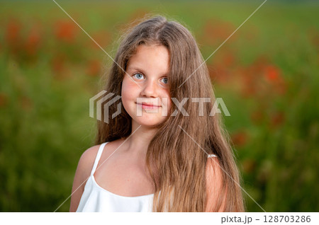 portrait of a girl on the background of a field of poppies in the evening sunlight, closeup 128703286