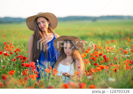 beautiful young woman with girl in straw hats in poppy field, happy family having fun in nature 128703326