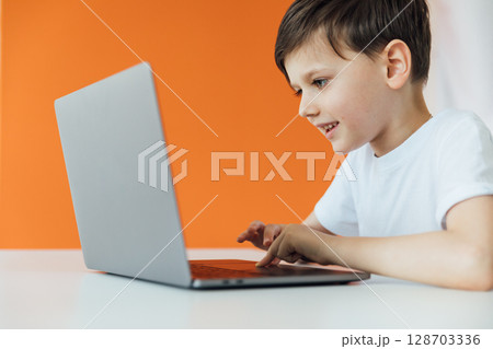 Boy working at desk with study laptop at school Boy working at desk with study laptop at school 128703336