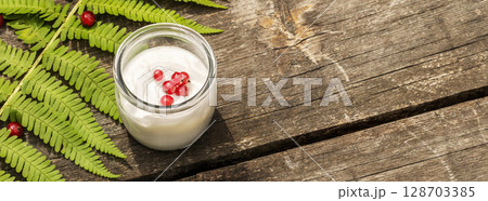 Healthy food banner with vegan homemade yogurt with red currant on wooden table with green fern leaf. Mindful and sustainable eating concept. Natural food and climate friendly eating. Copy space 128703385